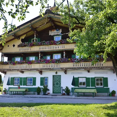 A charming country house with colorful flower balconies and a large garden. The architecture is typical for the alpine region.