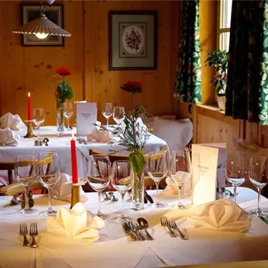 A cozy restaurant with elegantly set tables. Candlelight and fresh flowers create an inviting atmosphere.