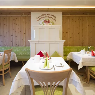 Ein einladendes Restaurant mit Holzwänden und hellen Tischen. Die Tische sind festlich mit bunten Servietten dekoriert.