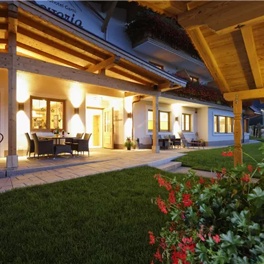 Ein einladendes Gebäude mit Holzarchitektur und beleuchtetem Eingangsbereich. Der gepflegte Garten lädt zum Verweilen ein.