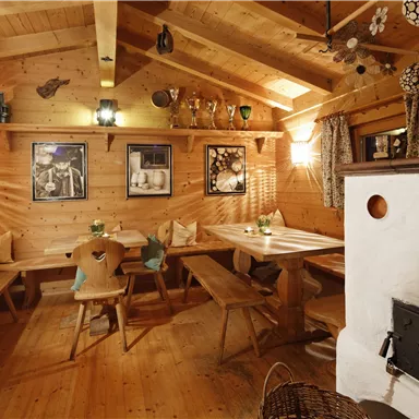 Ein gemütlicher Gastraum mit Holzdekor und rustikalen Tischen. An den Wänden hängen Bilder und die Atmosphäre ist warm und einladend.