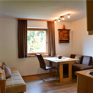 A cozy dining and living area with a table and chairs. Large windows provide plenty of daylight and an inviting atmosphere.