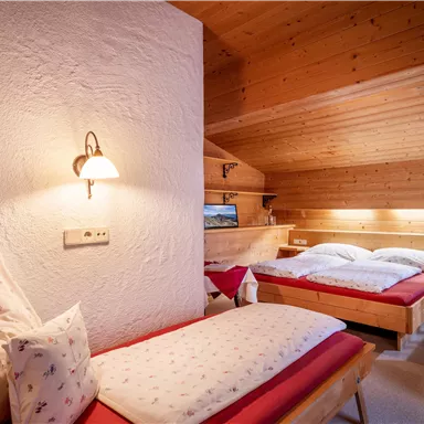 A cozy bedroom with wood paneling and two beds. The quiet atmosphere is accentuated by warm lighting and simple decoration.