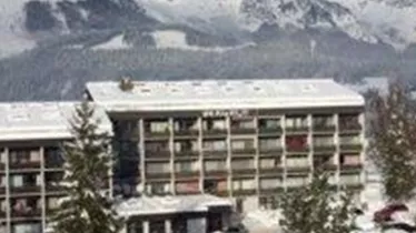 A modern hotel in a snow-covered landscape. In the background, majestic mountains rise under a clear sky.