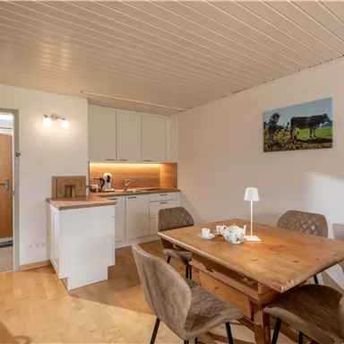 Eine gemütliche Küche mit einem Essbereich aus Holz. Die Wände sind hell und es gibt eine schöne Wanddekoration.