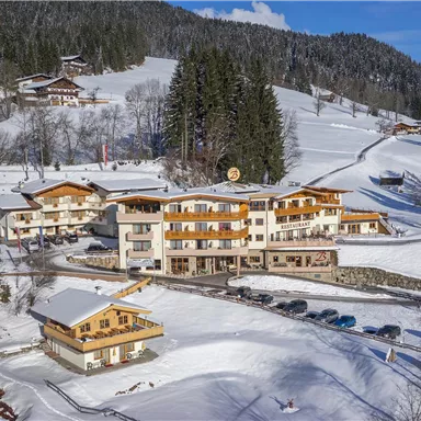 A picturesque hotel in the midst of a snowy landscape. Surrounded by trees and mountains, it radiates winter coziness.