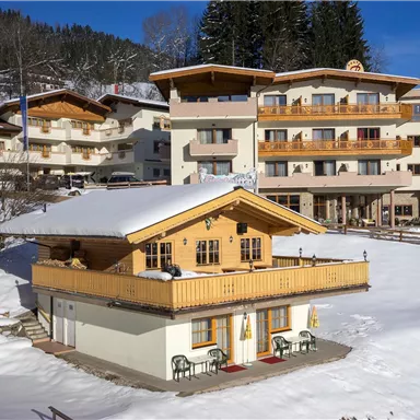 A picturesque alpine lodge in the snow, surrounded by mountains. The buildings are traditionally designed and radiate a cozy atmosphere.