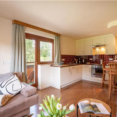 Eine helle und einladende Wohnung mit einer modernen Küche und gemütlichem Wohnbereich. Große Fenster sorgen für viel Tageslicht.