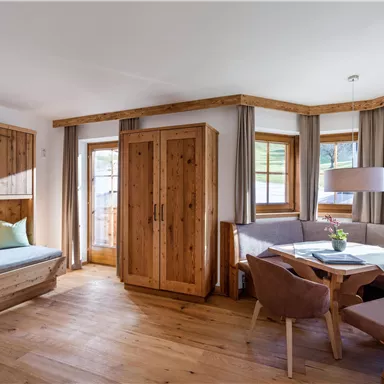 Ein gemütlicher Raum mit Holzdetails und großen Fenstern. Der Platz ist hell und einladend, mit einem Esstisch und Stühlen.