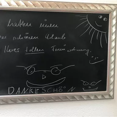 A blackboard with a friendly message and drawings. The text thanks for a pleasant stay in a holiday apartment.