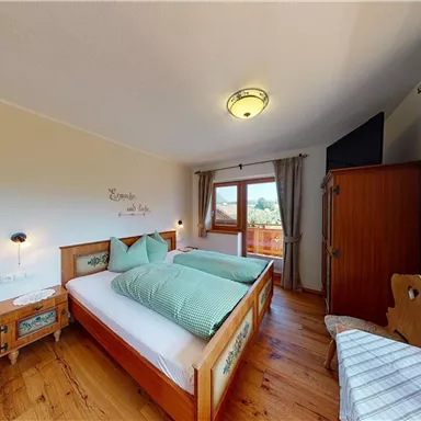 A cozy bedroom with two beds and wooden paneling. The room has large windows that offer a view of the outside.