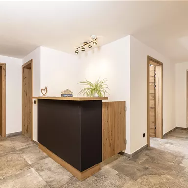 A modernly designed reception area with wooden and stone flooring. Several doors lead to different rooms.