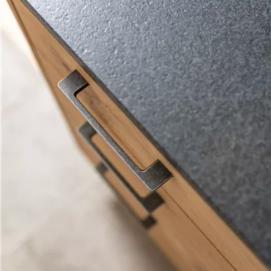 Eine moderne Küchenoberfläche aus dunklem Material mit Holzschrank und einem stilvollen Griff. Die Kombination aus Holz und Stein wirkt elegant und zeitgemäß.