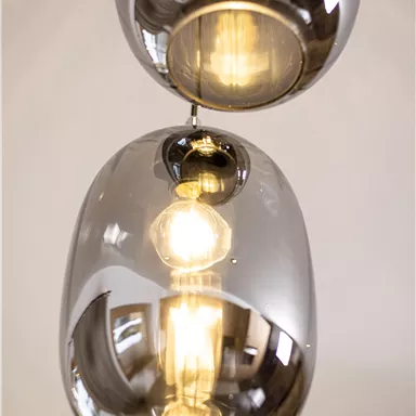 A modern pendant light with glass pendant housings. The light has warm illumination and reflects the surroundings.