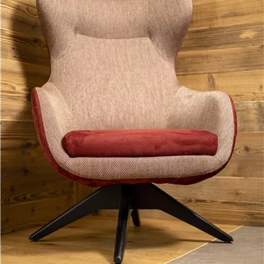 A modern, comfortable armchair with a gray and red cover. It stands in a wood-paneled room on a light floor.