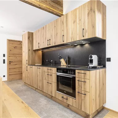 Eine moderne Küche mit Holzschränken und eleganten Oberflächen. Sie ist gut ausgestattet und hat viel Stauraum.