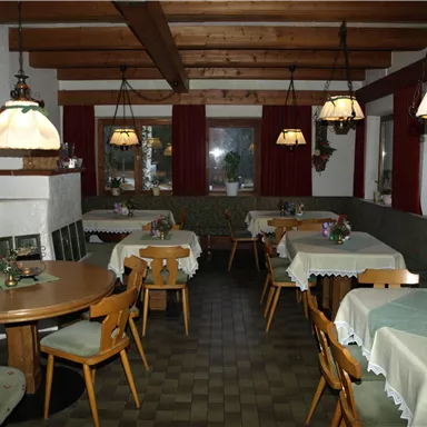 A cozy restaurant with wooden tables and chairs. Warm lighting and decorated tables create an inviting atmosphere.
