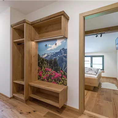 Ein moderner Flur mit Holzregalen und einer schönen Berglandschaft an der Wand. Zwei Türen führen zu Schlafzimmern mit einem gemütlichen Ambiente.