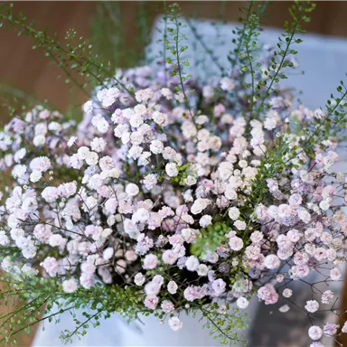 Ein wunderschöner Blumenstrauß mit kleinen rosa Blüten und zarten grünen Zweigen. Die Anordnung strahlt Frische und Natürlichkeit aus.