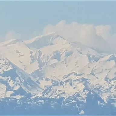 An impressive mountain landscape with snow-covered peaks and blue skies. The majestic mountains radiate tranquility and grandeur.