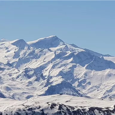An impressive mountain landscape with snow-covered peaks under a clear sky. The variety of rocks showcases the natural beauty of the Alps.