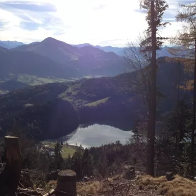 Eine herrliche Berglandschaft mit einem glitzernden See im Vordergrund. Der Himmel ist klar und die Berge erheben sich majestätisch im Hintergrund.