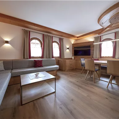 A modern living room with a cozy sitting area and wooden details. The large windows let in a lot of light and create an inviting atmosphere.