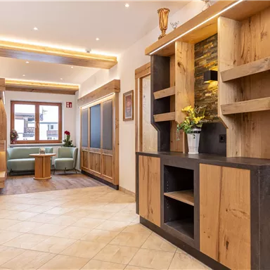 Ein einladender Flur mit modernen Holzregalen und hellem Licht. Auf der linken Seite steht eine gemütliche Sitzecke mit Pflanzen.