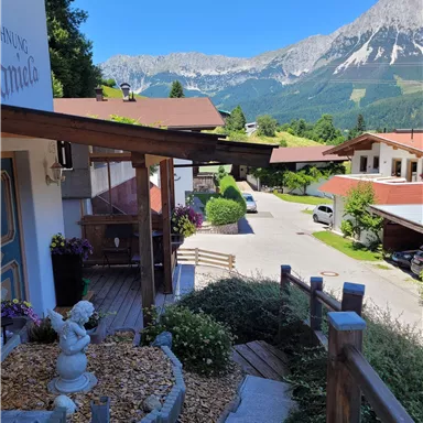 Eine schöne Aussicht auf die Berge von einem Balkon aus. Im Vordergrund sind Blumen und eine Treppe zu sehen.