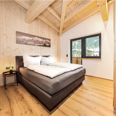 Ein modernes Schlafzimmer mit Holzverkleidung und einem großen Fenster. Das Bett ist komfortabel und die Atmosphäre ist gemütlich.