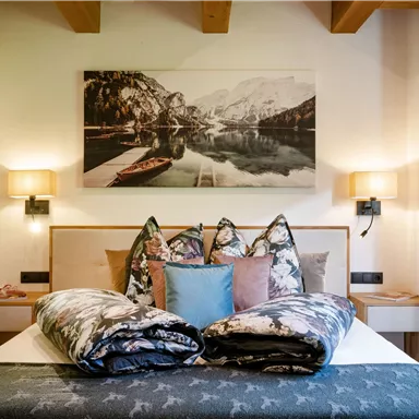 A cozy bedroom with a modern bed and decorative pillows. On the wall hangs a picture of a picturesque landscape.