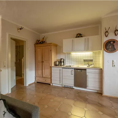 Eine gemütliche Küche mit modernen Geräten und einem Holzschrank. Der Raum hat helle Wände und einen warmen, einladenden Bodenbelag.