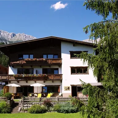 A charming house in alpine style, surrounded by mountains and trees. The sunny balconies invite you to relax.