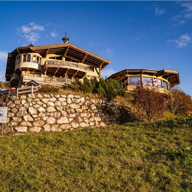 Eine malerische Berghütte auf einer Wiese mit schönen Ausblicken. Der Himmel ist klar und die Umgebung ist grün und einladend.