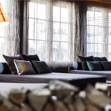 A modern room with large windows and soft sofas. Soft lighting and elegant cushions create an inviting atmosphere.