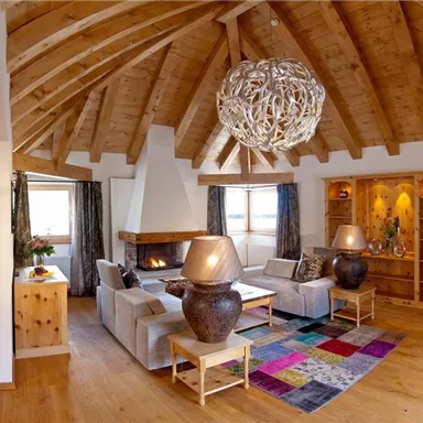 A cozy living room with a wooden ceiling, large windows, and modern furniture. The space is warm and inviting, perfect for relaxation.