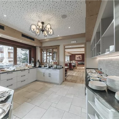 Ein eleganter Speiseraum mit einem Buffet und einem gemütlichen Ambiente. Helle Wände und Fenster sorgen für viel Licht.