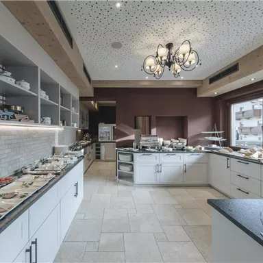 Eine moderne Küche mit hellen Wänden und einem großzügigen Essbereich. Auf den Tischen sind verschiedene Speisen und Getränke angerichtet.