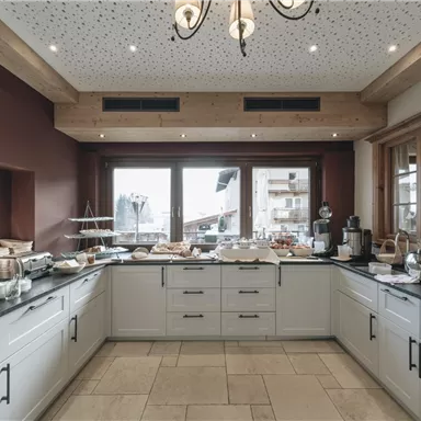 Ein modernes Frühstücksbuffet in einem hellen Raum. Die großen Fenster bieten einen Blick auf die Landschaft draußen.