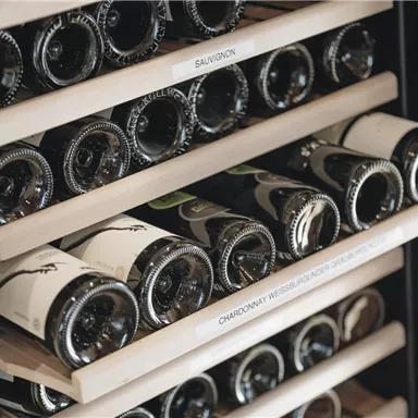Eine Weinlagerung mit mehreren Regalen voller Weinflaschen. Die Flaschen sind sortiert und beschriftet.