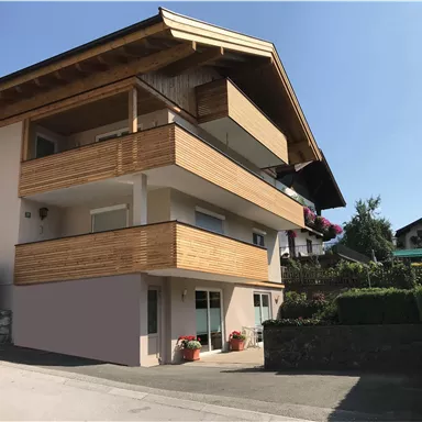 A modern house with wooden cladding and several balconies. It is situated in a quiet environment with a green garden.