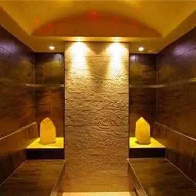 A modern wellness room with illuminated walls and a wooden bench. Soft lighting creates a relaxing atmosphere.