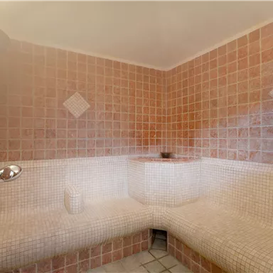 Ein entspannender Raum mit Fliesen in sanften Farben. Die Ecke ist gemütlich gestaltet, ideal für Erholung und Wellness.