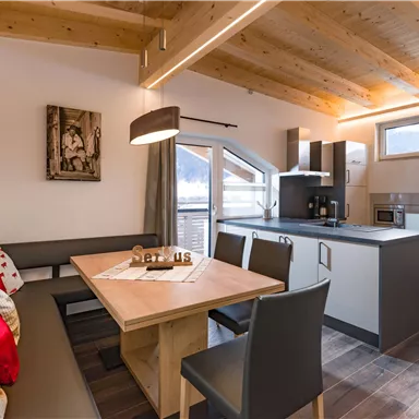 Moderne Küche mit gemütlichem Essbereich. Helle Holzdecke und große Fenster lassen viel Licht hinein.