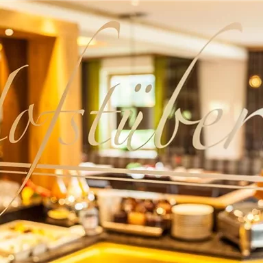 Ein gemütlicher Innenraum mit einem Buffet und klarer Beschriftung „Hofstüberl“. Die warme Atmosphäre lädt zum Verweilen ein.