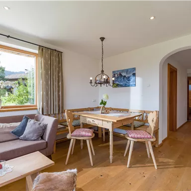 A cozy living room with a sofa and a dining table.
Large windows let in plenty of light and offer a view of nature.