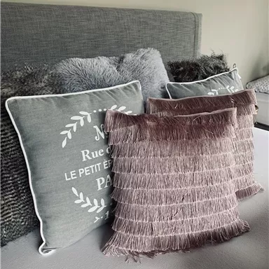 A cozy bed with several decorative pillows. The pillows have various textures and colors that give the room an inviting atmosphere.