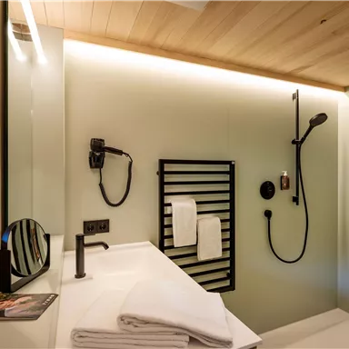 A modern bathroom with an elegant shower and a washbasin. Towels and a mirror complete the stylish design.