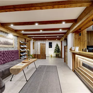 A stylish reception area with wooden beams and a cozy sofa. A small Christmas tree and warm light accents create an inviting atmosphere.