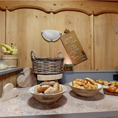 A cozy breakfast area with fresh fruit and various rolls. The wooden paneling creates an inviting atmosphere.